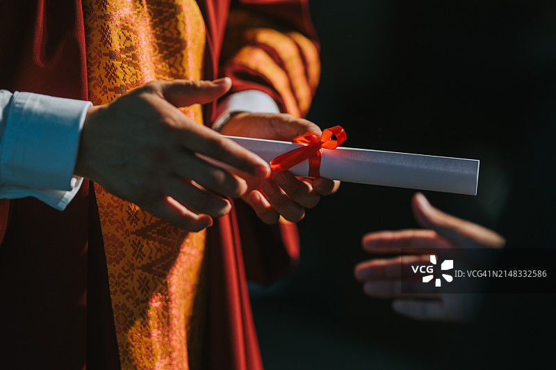 毕业典礼上亚洲院长在礼堂舞台上向大学毕业生颁发毕业证书特写图片素材