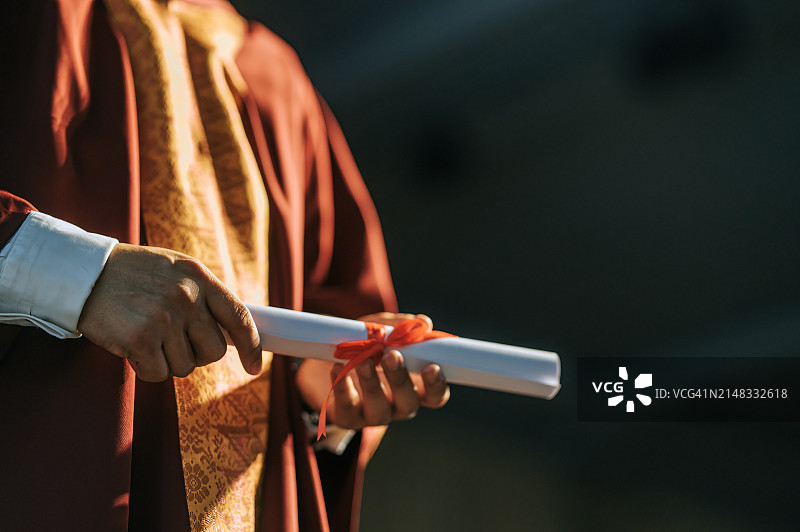 亚洲院长在礼堂舞台上拿着毕业证书的特写图片素材