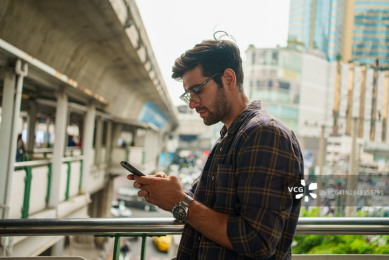 使用智能手机和笔记本电脑的年轻男人。以科技为中心的环境中的人们图片素材