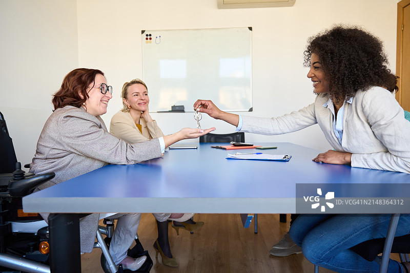 坐在轮椅上接收房屋钥匙——贷款、抵押、房地产概念图片素材