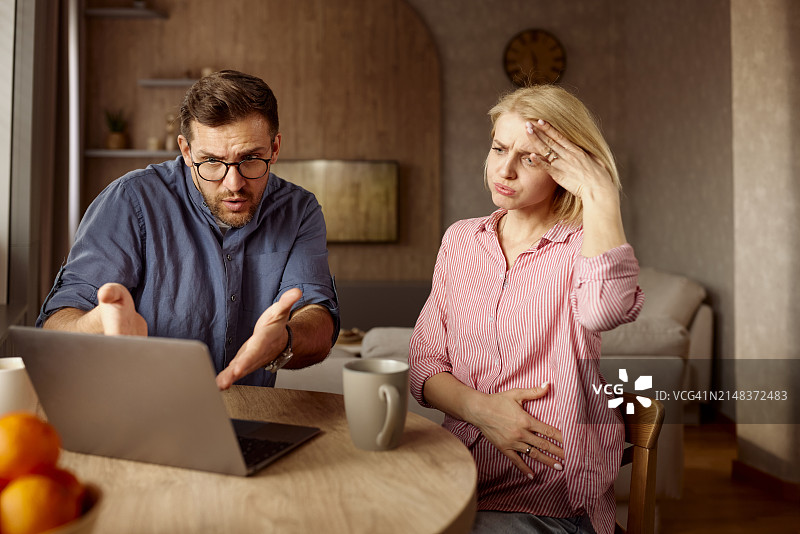 沮丧的夫妇在家阅读笔记本电脑上的问题邮件图片素材