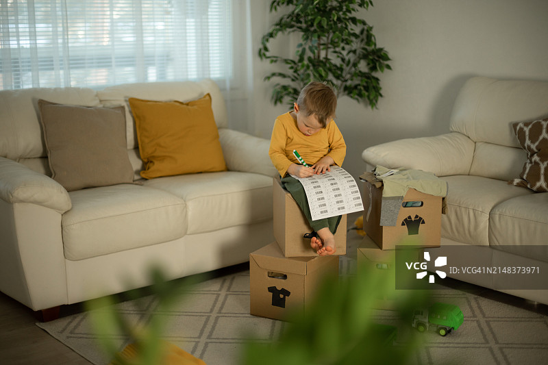 快乐的男孩把二手衣服放进捐赠箱图片素材