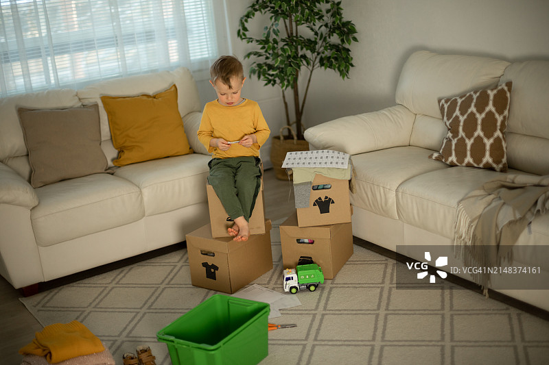 快乐的男孩把二手衣服放进捐赠箱图片素材