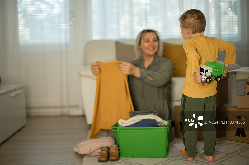 母亲和儿子将衣服装进箱子以备后用图片素材