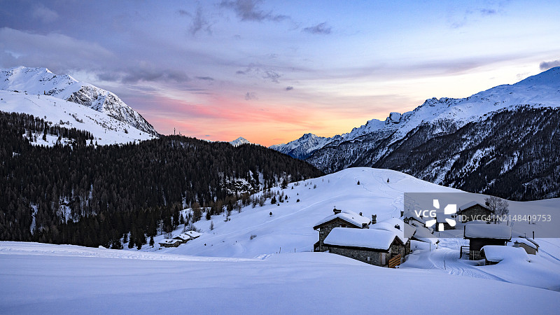 冬日日落：白雪覆盖的山间小屋图片素材