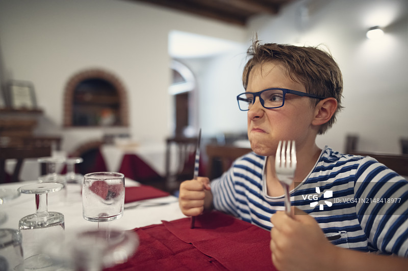 在餐厅焦急等待点餐的饥饿男孩图片素材