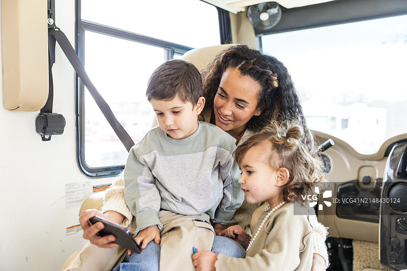 在房车里，母亲和孩子们一起在手机上看视频图片素材