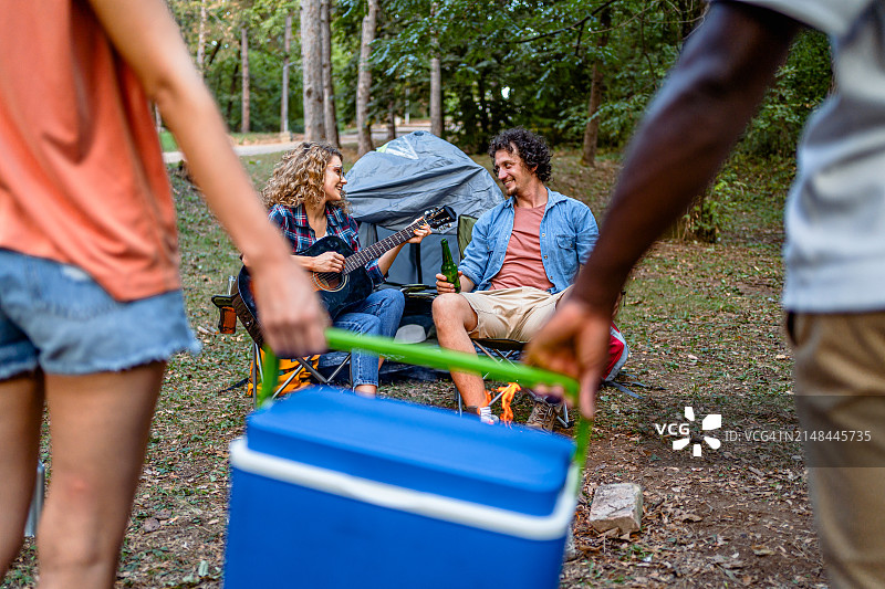 朋友们在野外露营时携带冷藏箱图片素材
