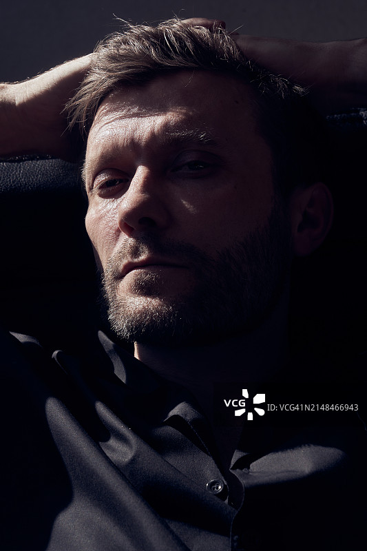 身穿黑衬衫的商务男士在办公室皮椅上休息特写图片素材