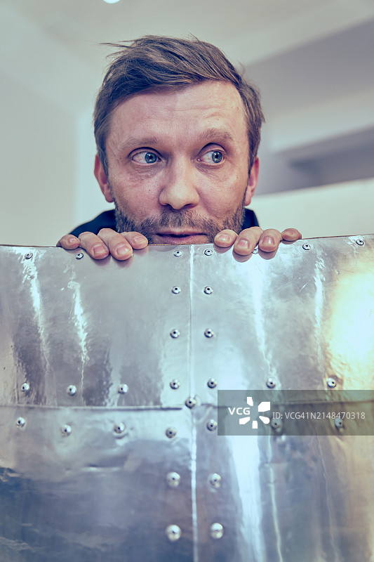 隐藏在飞行员椅背后的英俊络腮胡男子肖像，坐在金属椅子上的男人，成年人恐惧的概念，男人在躲藏图片素材