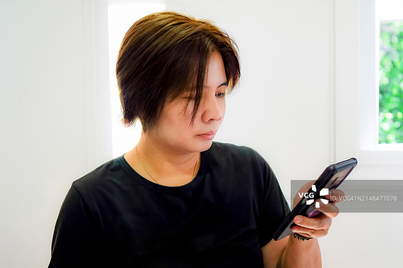 年轻女子在家中使用智能手机查看天气影像图片素材