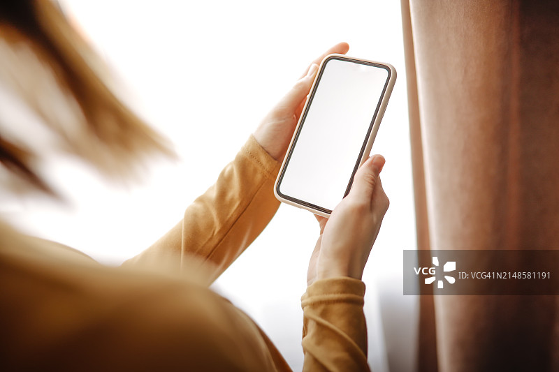 女士手持智能手机特写，中性色调图片素材