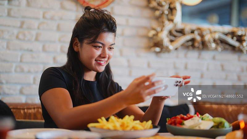 年轻女子在咖啡馆拍摄食物和饮料图片素材