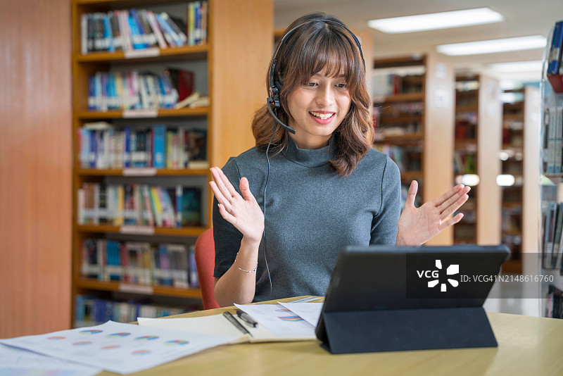 亚洲女学生在图书馆用电脑笔记本与老师进行视频会议式在线学习。重返校园教育知识大学概念。年轻女性工作并使用电脑笔记本。图片素材