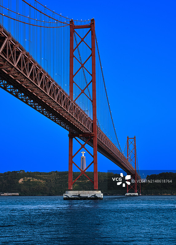 葡萄牙里斯本，四月二十五日大桥在傍晚时分被照亮，基督国王纪念碑完美地位于桥墩中央图片素材