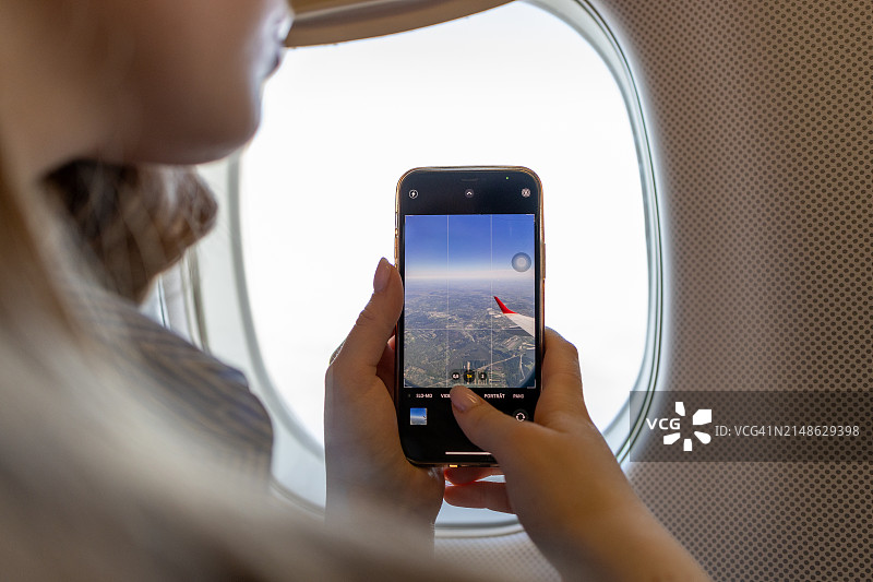 女孩从飞机窗外拍照图片素材