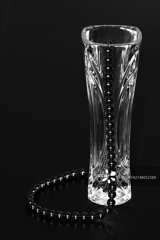 黑色赤铁矿珠子和玻璃水晶花瓶，黑色背景 - 低调图片素材