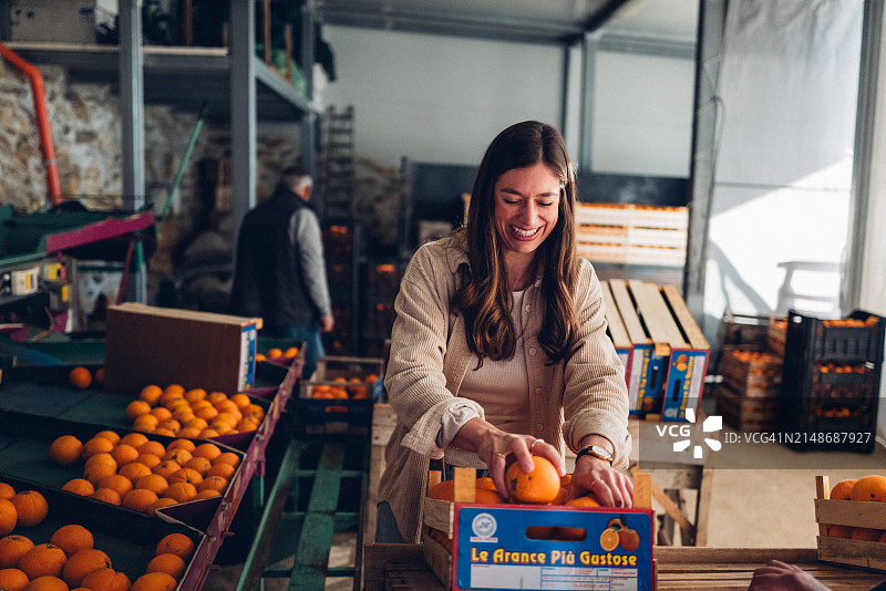 在仓库中装满橙子箱子的女人图片素材