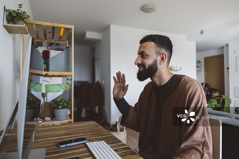 在家中参加视频会议的微笑的阿拉伯络腮胡男人图片素材