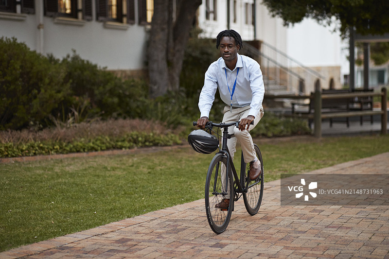 在人行道上骑自行车的年轻男教授图片素材