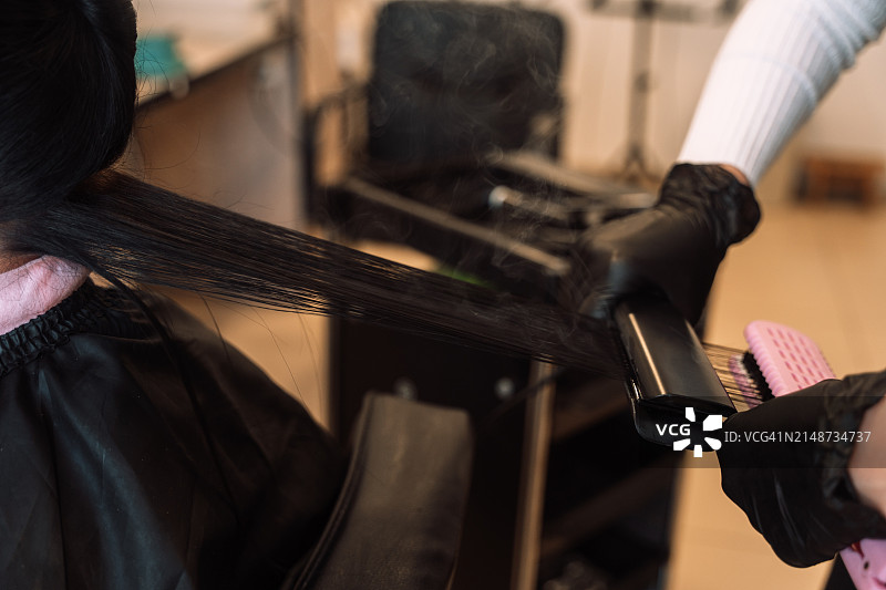 发型师使用特氟龙涂层拉直器蒸发头发中的角蛋白和肉毒杆菌图片素材