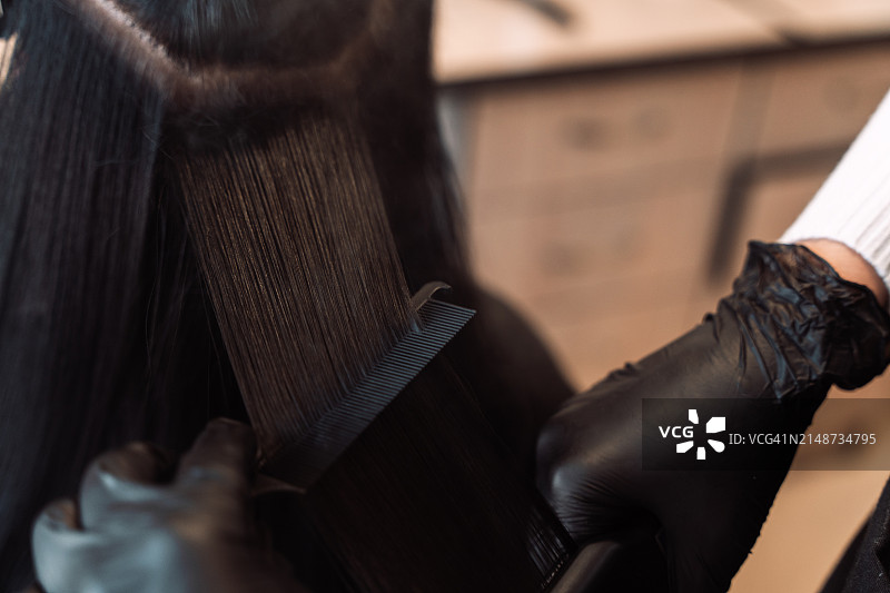 发型师使用特氟龙涂层拉直器蒸发头发中的角蛋白和肉毒杆菌图片素材