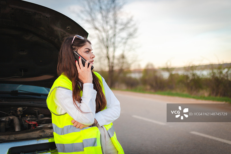 在路边穿着黄色背心呼救的年轻女人图片素材