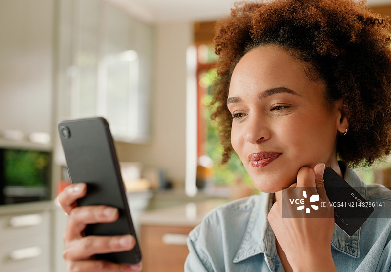 非洲女人在家用信用卡在智能手机上进行电商购物图片素材