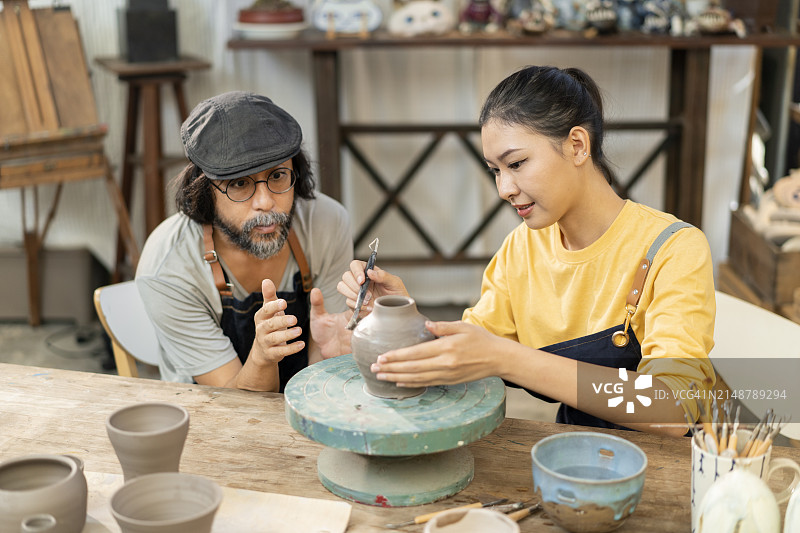 年长的男人在他的工作室里教女人们陶艺图片素材