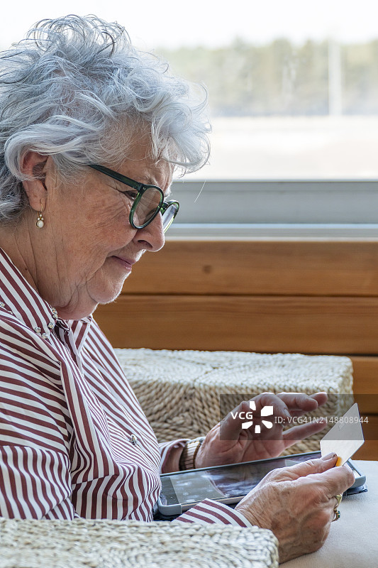 年长的女人看着信用卡，侧视图图片素材