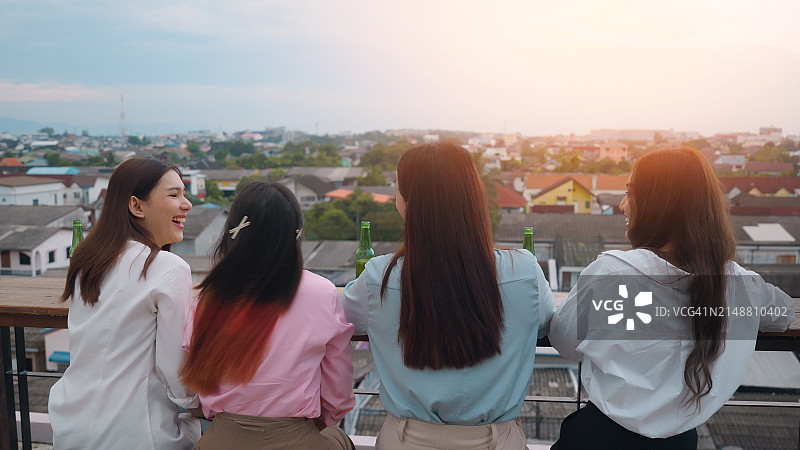 四名年轻人在屋顶派对上举杯庆祝图片素材