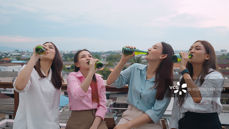 四名年轻人在屋顶派对上举杯庆祝图片素材