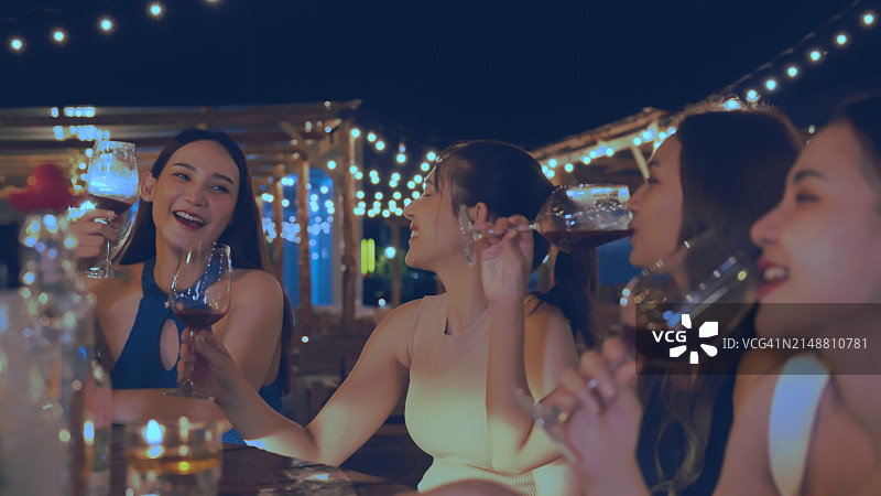 一群迷人的女人在豪华酒吧享受和开心聚会，一起喝花式鸡尾酒。快乐的女性朋友在城市夜总会庆祝节日活动图片素材