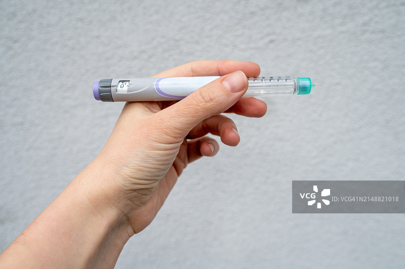 手持预装胰岛素笔，准备使用图片素材