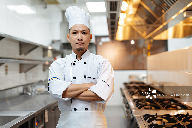 自信的亚洲厨师在厨房里交叉双臂站立图片素材