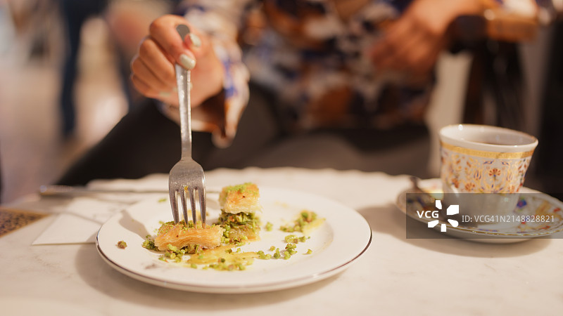 体验和吃土耳其甜点果仁蜜饼的多种族女性独自旅行者图片素材