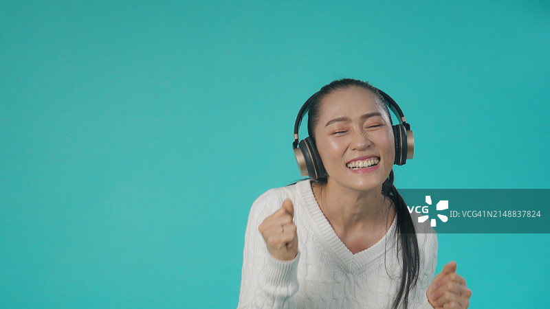 戴着耳机跳舞的快乐亚洲女人图片素材