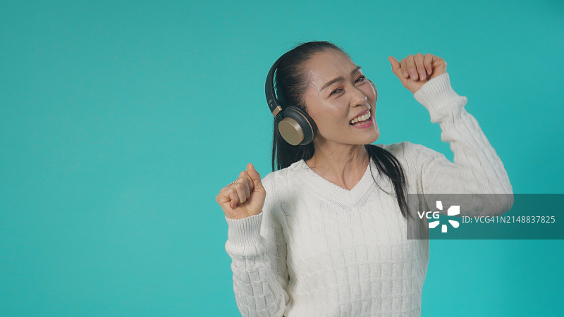 戴着耳机跳舞的快乐亚洲女人图片素材