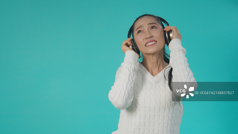 戴着耳机跳舞的快乐亚洲女人图片素材