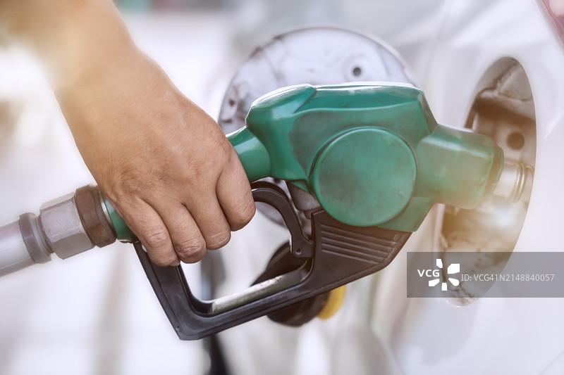 交通运输概念：手持燃油喷嘴在加油站给汽车加油图片素材