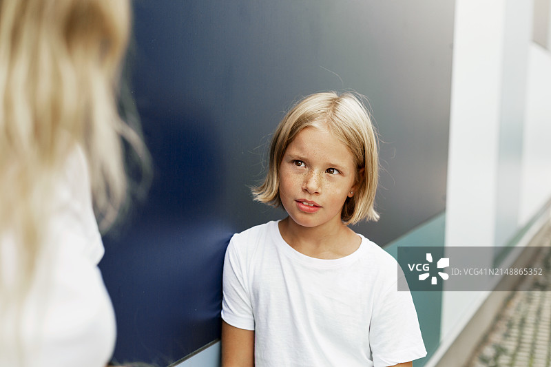 金发男孩靠在墙上看着母亲图片素材