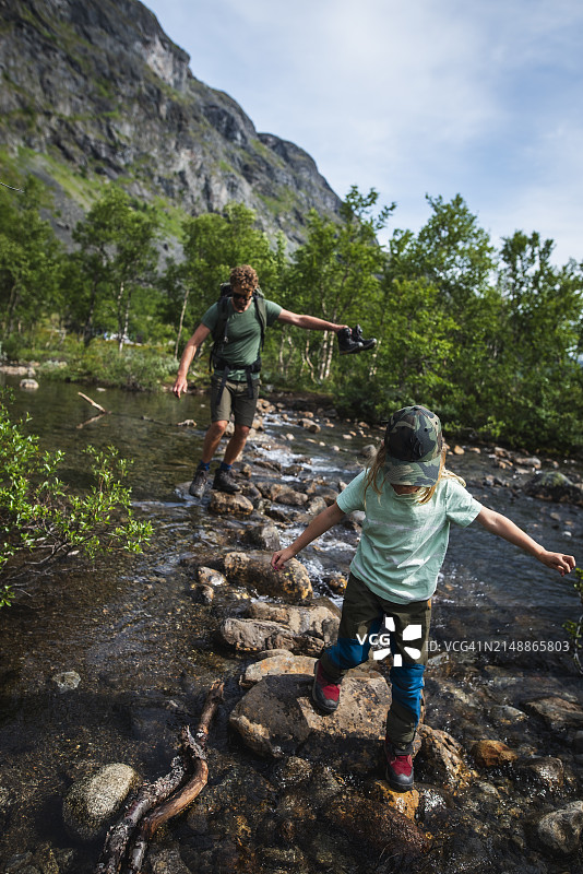 父女在森林中过河时走在岩石上图片素材