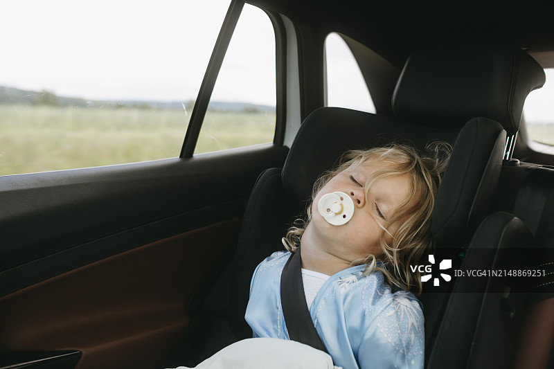 周末乘车旅行时口含奶嘴睡觉的女孩图片素材