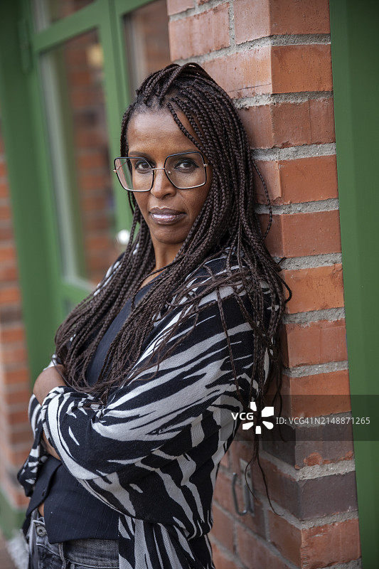 编发的中年妇女靠在砖墙上图片素材