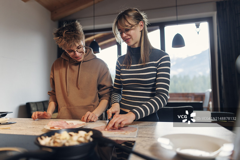 母亲和十几岁的孩子一起快乐地准备自制披萨图片素材
