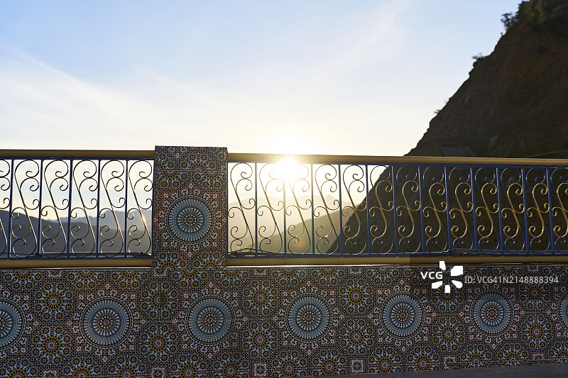阳光明媚的日子里，户外屋顶的金属栏杆，背景是山图片素材
