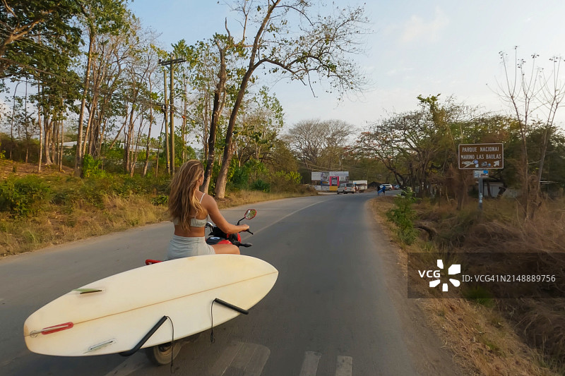 骑摩托车去海滩的女人（带冲浪板）图片素材