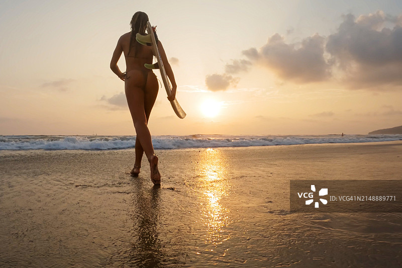 低角度日落海滩冲浪的女人图片素材