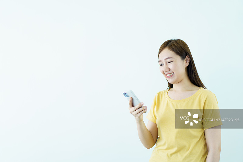 身穿亮黄色服装的女人在白色背景上使用手机图片素材