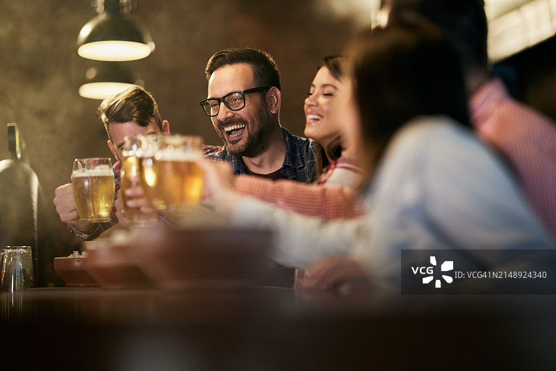 在酒吧里，快乐的朋友们举杯啤酒庆祝图片素材
